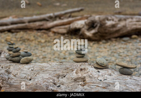 De petits tas de pierres empilées sur un bois flottant journal à Ruby Beach sur la côte du Pacifique Washingtons Banque D'Images