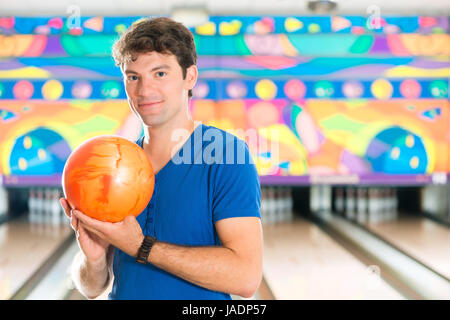 Jeune homme de bowling s'amuser, les lecteurs de l'homme tenant une boule de bowling en face de la ten pin alley Banque D'Images