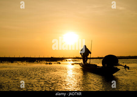 Pêcheur sur un petit bateau de pêche tôt le matin pour mettre en filet de pêche dans le réservoir local vers le bas le sud de la Thaïlande Banque D'Images