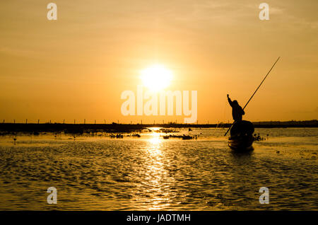 Pêcheur sur un petit bateau de pêche tôt le matin pour mettre en filet de pêche dans le réservoir local vers le bas le sud de la Thaïlande Banque D'Images
