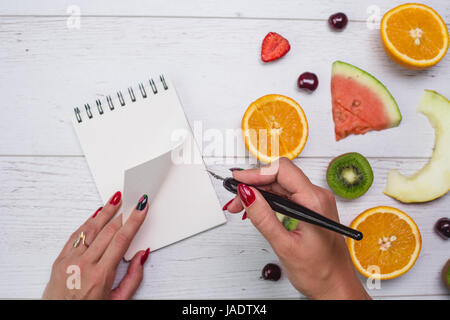 Vue de dessus du girl's hands, placés sur le bureau blanc avec des fruits. Banque D'Images