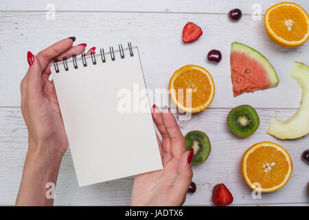 Vue de dessus du girl's hands, placés sur le bureau blanc avec des fruits. Banque D'Images