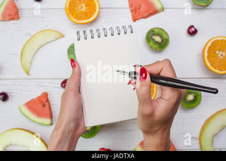 Vue de dessus du girl's hands, placés sur le bureau blanc avec des fruits. Banque D'Images