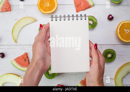 Vue de dessus du girl's hands, placés sur le bureau blanc avec des fruits. Banque D'Images