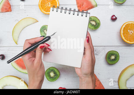 Vue de dessus du girl's hands, placés sur le bureau blanc avec des fruits. Banque D'Images