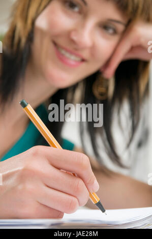 Kopf-und-Schulter-Ansicht eines jungen Frau am Tisch, brünetten Schreibstift sitzend mit der und Schnellhefter en main vor sich liegend Banque D'Images