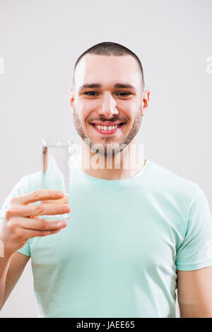 Jeune homme est holding glass of water. Banque D'Images