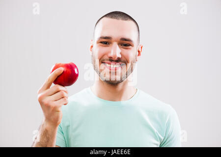 Jeune homme tenant une pomme et souriant. Banque D'Images