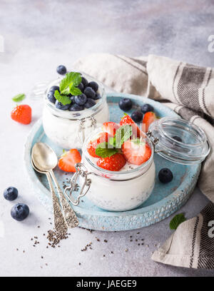 Chia Pudding pour le petit-déjeuner dans des bocaux en verre garni de Berry en deux parties sur fond noir en gris clair avec une serviette et de cuillères. Copier l'espace. Banque D'Images