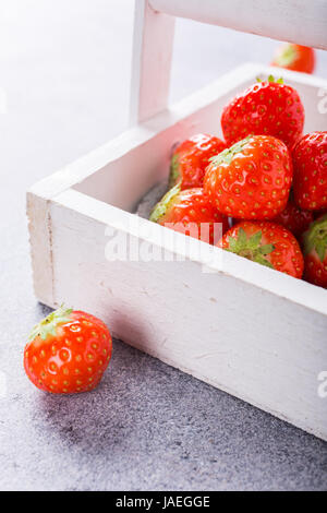 Boîte en bois blanc rempli de succulentes fraises rouge frais mûrs juteux sur table en pierre grise. Alimentation saine. Copier l'espace. Banque D'Images