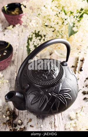 Théière noire en fonte avec la médecine en santé le thé vert avec fleur sur table en bois blanc avec des branches de fleurs. Copier l'espace. Banque D'Images