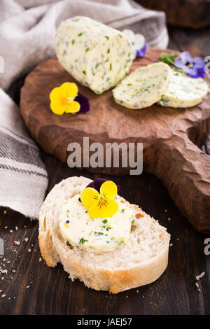 Sandwich avec du beurre aux fines herbes et fleurs comestibles sur fond de bois, alimentation saine. Banque D'Images