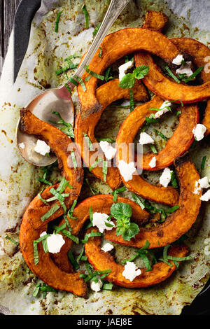 Citrouille cuite rôtie, avec plus d'herbes aromatiques, fromage de chèvre et de la menthe. Concept d'aliments sains avec copie espace. Banque D'Images