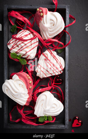 Des meringues en forme de coeur dans la vieille boîte en bois pour la Saint-Valentin, vue du dessus. Banque D'Images