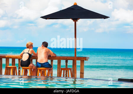 Réussir sa retraite, des loisirs de l'été vacances. Couple retraités bénéficiant belle journée ensoleillée en piscine du club de plage. Banque D'Images