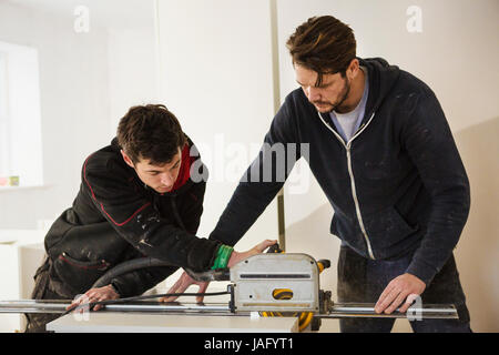 Deux constructeurs, placoplâtre coupe avec une scie circulaire. Banque D'Images