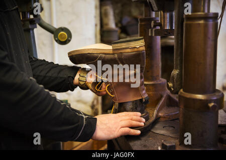 Close up de travailleur dans un atelier de cordonnier, à l'aide d'une machine pour faire une cheville boot. Banque D'Images