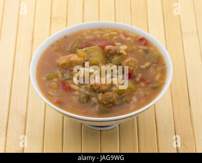 Une portion de riz, viandes de gumbo et de légumes dans un bol sur un napperon en bois. Banque D'Images