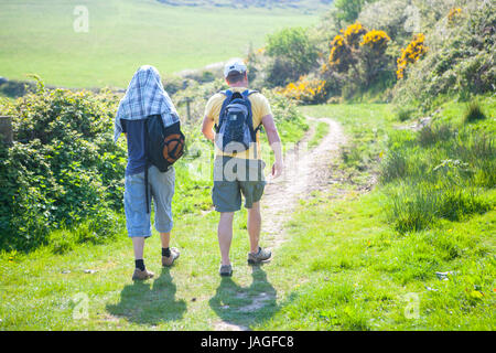 Deux hommes à marcher le long des sentiers de pays vert enjoying outdoor randonnées et de soleil Banque D'Images