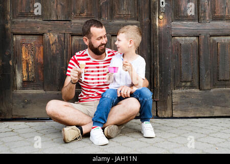 Jeune père et son petit-fils la consommation de crème glacée. Journée ensoleillée. Banque D'Images