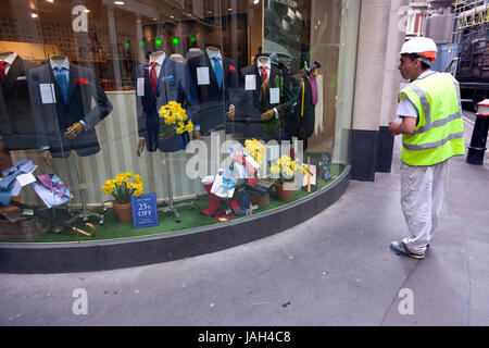 Londres, Royaume-Uni, 7 mai 2017 : travailleur avec casque regarder des vêtements au magasin de mode avec des costumes pour les hommes d'affaires dans City of london Banque D'Images