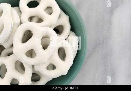 Haut de page Fermer la vue de yogourt bretzels couverts dans un bol vert au sommet d'une planche à découper en marbre gris. Banque D'Images