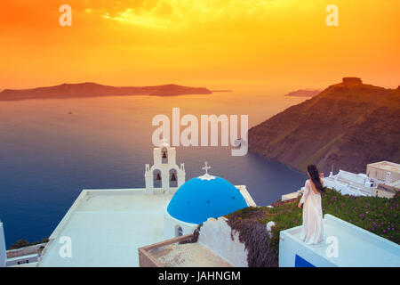 Coucher du soleil brillant à Fira avec une église et une épouse sur un toit, Santorini, Grèce. Banque D'Images