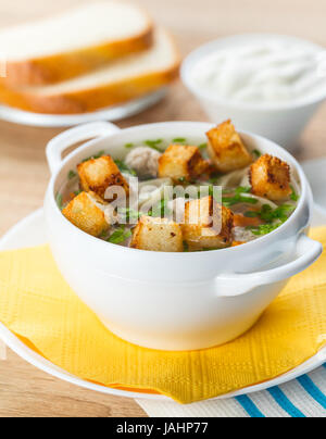 Soupe avec des boulettes de viande et les nouilles dans une assiette blanche Banque D'Images