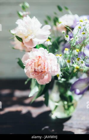 Bouquet de pivoines blanches, camomille et iris fleurs dans vase en verre. Arrière-plan de l'été. Photo teinté Banque D'Images