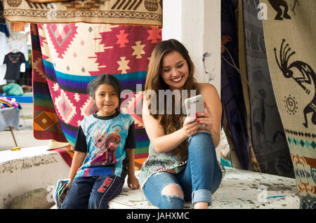 Lexington, Kentucky - 17 MAI 2017 : belle jeune femme regardant son portable à côté d'une petite fille, autochtones non identifiés dans des tissus colorés background Banque D'Images