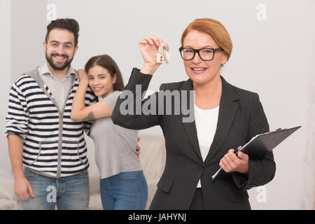 Agent immobilier joue avec les touches de nouvel appartement loué par couple. Banque D'Images