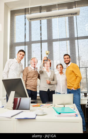 L'équipe gagnant holding trophy fiers et heureux de leur succès Banque D'Images