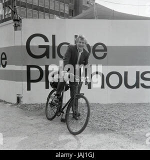 L'acteur et réalisateur Sam Wanamaker sur sa bicyclette à l'extérieur de son site proposé pour le Globe Playhouse Theatre à Londres en 1972. La Sam Wanamaker Playhouse est un théâtre intérieur faisant partie de Shakespeare's Globe, de même que le Globe Theatre, London Bankside sur. Construit en utilisant des plans du 17e siècle pour un théâtre intérieur, la Playhouse rappelle la mise en page et le style du théâtre de Blackfriars, bien qu'il n'est pas une reconstruction exacte. Sa coquille a été construit lors de la construction de la complexité du Globe de Shakespeare, remarquable pour la reconstruction de l'open-air Globe Theatre de la même période. Banque D'Images