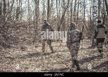 Scène de chasse avec groupe de chasseurs à pied, en tenue de camouflage dans la forêt du printemps avec des feuilles sèches pendant la saison de la chasse Banque D'Images
