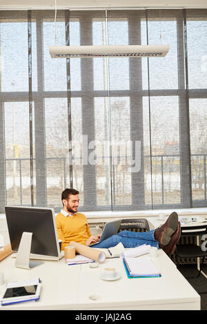 Businessman typing sur son ordinateur portable tout en travaillant sur internet article Banque D'Images
