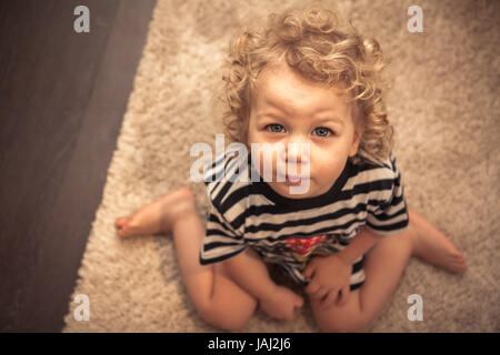 Mignon bébé implorant curly girl and looking at camera avec vue de dessus Banque D'Images