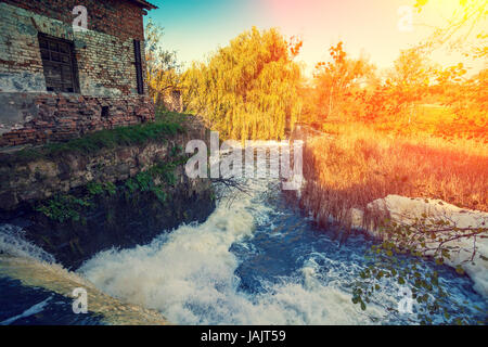 Cascade et moulin à eau au coucher du soleil Banque D'Images