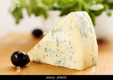 Un gros morceau de fromage et d'olives noires Banque D'Images