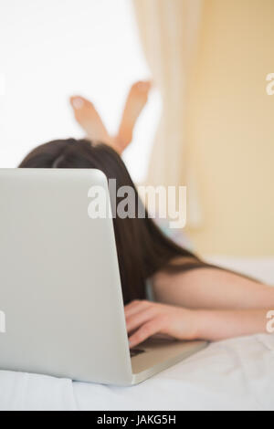 Ordinateur portable couvrant les filles rencontrent le lit dans la chambre à la maison Banque D'Images