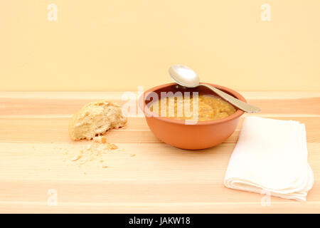 Spoon reposant sur un bol de soupe de légumes, avec la moitié d'un morceau de pain et une serviette Banque D'Images