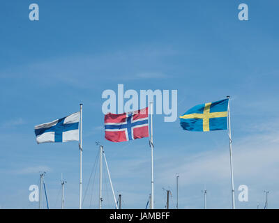 Trois drapeaux scandinaves dans une marina sur un ciel d'été bleu Banque D'Images