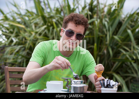Mid adult man drinking tasse de café ou de thé à l'extérieur en plein air holding glace au chocolat dans la main Banque D'Images