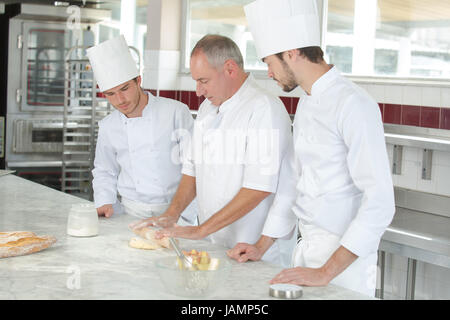 L'apprentissage des étudiants culinaires comment mélanger la pâte en cuisine Banque D'Images