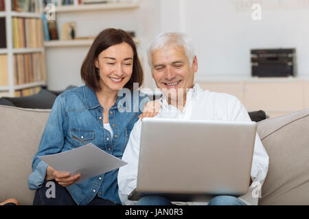 Couple à l'aide de leur ordinateur portable pour payer leurs factures à la maison dans le salon Banque D'Images