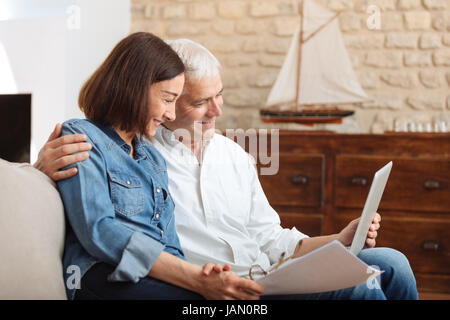 Couple à l'aide de leur ordinateur portable pour payer leurs factures à la maison dans le salon Banque D'Images