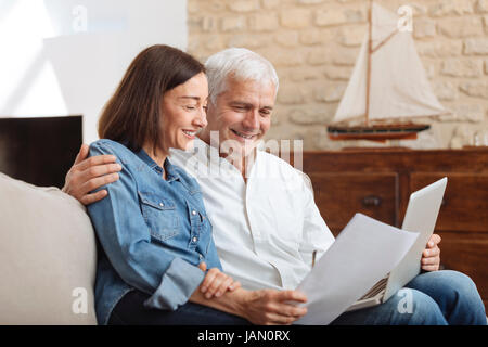 Couple à l'aide de leur ordinateur portable pour payer leurs factures à la maison dans le salon Banque D'Images