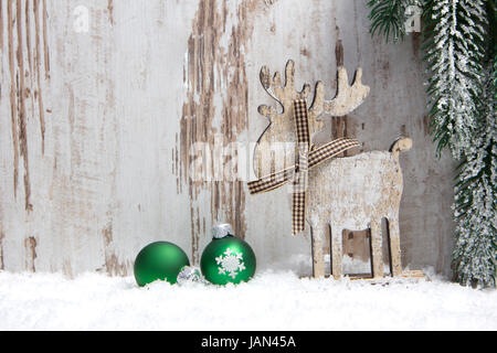 Weihnachten, Dekoration, Holzhintergrund mit Schnee, Elch, grün und einem Tannenzweig Weihnachtskugeln Banque D'Images
