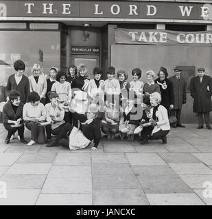 1965, historiques, compétitrices posent pour une photo à l'extérieur du pubis Lord Wellington house dans le Old Kent Road, Peckham, Londres dans leurs tabliers et avec leurs poêles à frire avant l'Assemblée Mardi Gras pancake race. Banque D'Images