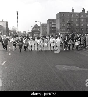 En 1965, Old Kent Road, Peckham, Londres et un groupe de femmes dans leurs tabliers et de transporter les casseroles pour le traditionnel Mardi Gras panacke la race. Banque D'Images