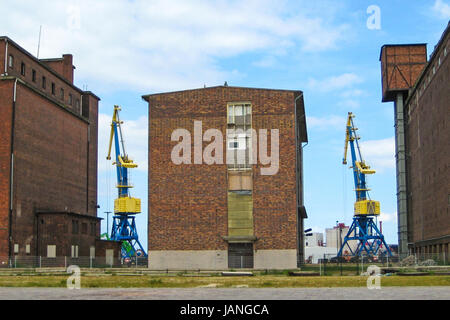 Grues colorées entre les anciens bâtiments en brique au port de hanséatique Wismar Banque D'Images